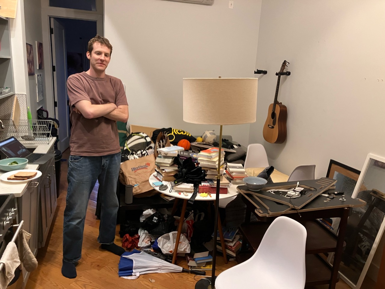 A person standing beside a table piled with books and belongings